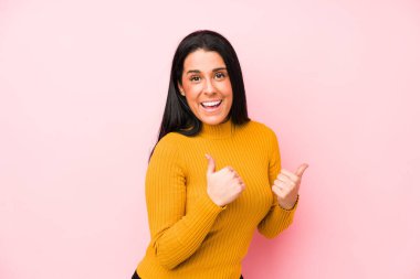 Pembe arka planda soyutlanmış beyaz bir kadın. Baş parmağını kaldırıyor, gülümsüyor ve kendinden emin..