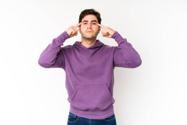 Beyaz arka planda izole edilmiş genç bir adam bir göreve odaklanmış, işaret parmaklarını işaret ediyor..