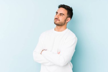 Kafkasyalı genç adam mavi arka planda izole edilmiş hedeflerine ve amaçlarına ulaşma hayali kuruyor.