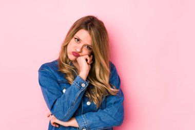 Pembe arka planda izole edilmiş genç beyaz kadın tekrarlanan bir görevden bıktı..