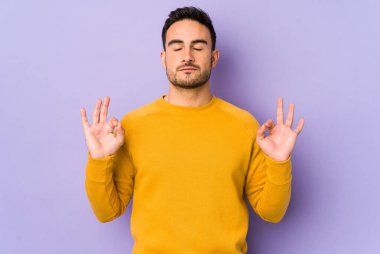 Mor arka planda izole edilmiş genç beyaz adam sıkı çalışma gününden sonra rahatlıyor. Yoga yapıyor..