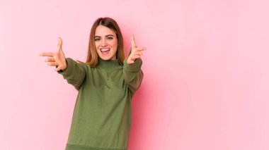 Pembe arka planda izole edilmiş genç beyaz kadın kameraya sarıldığı için kendinden emin..