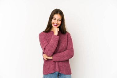 Beyaz arka planda izole edilmiş genç beyaz kadın mutlu ve kendinden emin gülümsüyor, elleriyle çenesine dokunuyor..