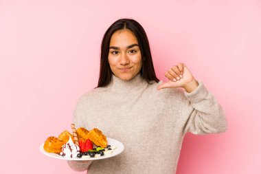 İzole edilmiş bir waffle tutan genç Asyalı kadın gururlu ve kendinden emin hissediyor, örnek olarak.