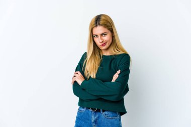 Beyaz arka planda izole edilmiş, hoşnutsuzca kaşlarını çatan, kollarını kavuşturan genç sarışın kadın..