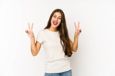Beyaz arka planda izole edilmiş genç beyaz kadın zafer işareti gösteriyor ve gülümsüyor..