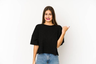 Beyaz arka planda izole edilmiş genç beyaz kadın işaret parmağıyla fotokopi alanını işaret ederek şok oldu..