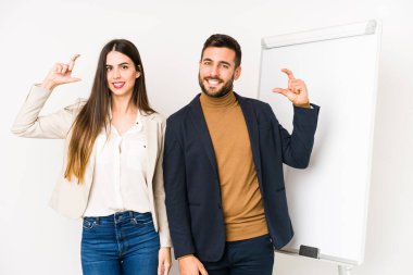 Kafkasyalı genç bir iş çifti, izole edilmiş, işaret parmaklarıyla bir şey tutuyorlar, gülümsüyorlar ve kendilerine güveniyorlar..