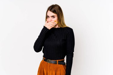 Beyaz arka planda izole edilmiş beyaz tenli genç bir kadın elleri endişeli bir şekilde ağzı örtüyor..
