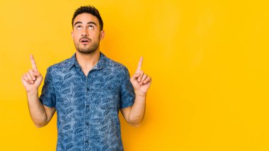 Genç beyaz adam sarı fırında izole edilmiş, ağzı açık, üst tarafı işaret ediyor..