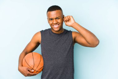 Basketbol oynayan genç Kolombiyalı adam kulaklarını elleriyle kapatıyor..