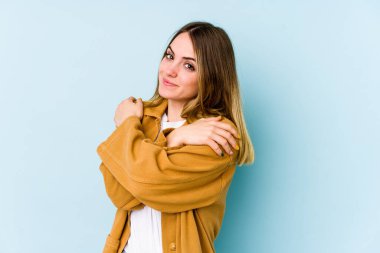 Kafkasyalı genç kadın mavi arka planda izole edilmiş, güler yüzlü ve mutlu..