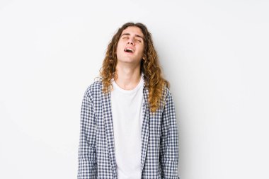 Genç, uzun saçlı, yalnız poz veren rahat ve mutlu bir gülüş, boynunda dişler olan bir adam..