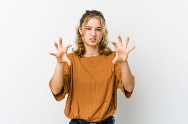 Beyaz arka plandaki genç beyaz kadın pençelerini kedi taklidi yaparken gösteriyor, agresif bir hareket..