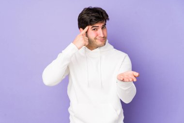 Mor arka planda izole edilmiş genç bir adam elinde bir ürün tutuyor..