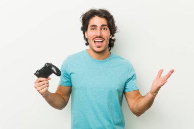 Bir zafer ya da başarı kutlayan bir oyun denetleyicisi tutan genç adam