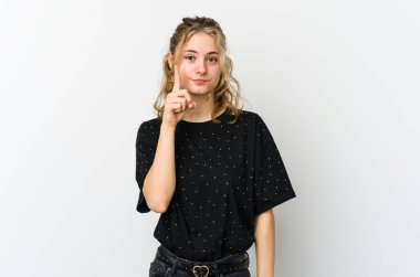 Beyaz arka plandaki genç beyaz kadın bir numarayı parmaklarıyla gösteriyor..