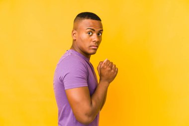 Sarı arka planda izole edilmiş genç Latin adam korkmuş ve korkmuş..