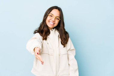 Latin kökenli genç bir kadın kameraya el uzatarak selam veriyor..