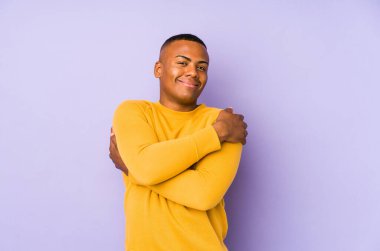 Mor arka planda izole olmuş genç Latin adam sarılmalar, kaygısız gülümsemeler ve mutlu..