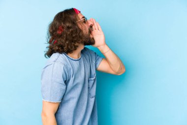 Genç, uzun saçlı, festival elbisesi giyen hippi kılıklı, bağıran ve ağzı açık avucunda avuç içi tutan bir adam..