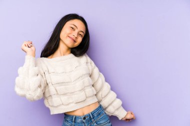 Mor bir arka planda izole edilmiş genç Çinli kadın dans ediyor ve eğleniyor..