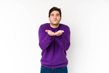 Genç adam beyaz arka planda izole edilmiş dudaklar kıvrılmış ve hava öpücüğü göndermek için avuç içleri tutulmuş..