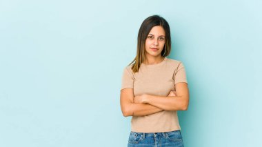 Mavi arka planda izole edilmiş, sıkılmış, yorgun ve dinlenmeye ihtiyacı olan genç bir kadın..