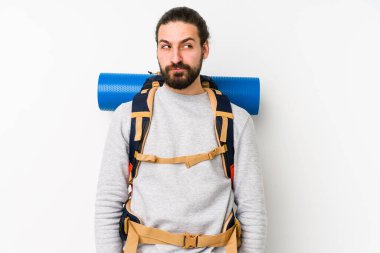 Beyaz bir arka planda izole edilmiş genç bir sırt çantalı kafası karışmış, şüpheli ve güvensiz hissediyor..