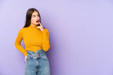 Mor arka planda soyutlanmış beyaz bir kadın şüpheli ve şüpheci bir ifadeyle yana bakıyor..