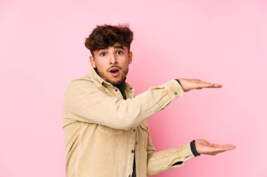 Arka planda poz veren genç bir Arap adam elleri arasında bir kopya alanı tutarken şok olmuş ve hayrete düşmüştü..