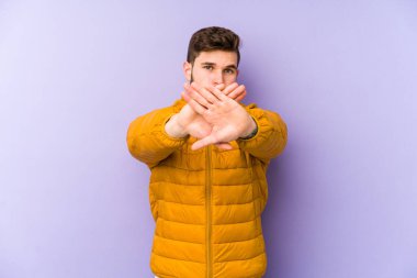 Mor arka planda izole edilmiş genç bir adam inkar hareketi yapıyor.