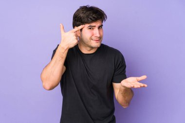 Mor arka planda izole genç adam işaret parmağıyla bir hayal kırıklığı jesti gösteriyor..