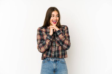 Beyaz arka planda izole edilmiş genç beyaz kadın ellerini çenesinin altında tutuyor, mutlu bir şekilde yana bakıyor..