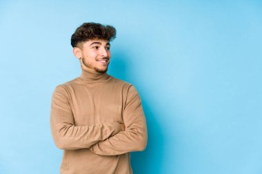 Genç Arap adam kendini izole edip kollarını kavuşturarak gülümsüyor..