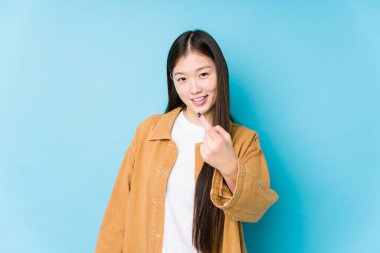 Mavi arka planda poz veren genç Çinli kadın seni işaret ederek sanki seni davet ediyormuş gibi..