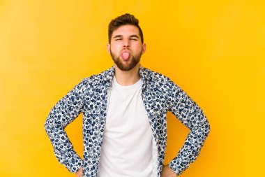 Sarı arka planda izole edilmiş beyaz bir genç. Komik ve dost canlısı bir dil uzatıyor..