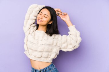 Mor arka planda izole edilmiş genç Çinli bir kadın. Kollarını uzatıyor, rahat bir konumda..