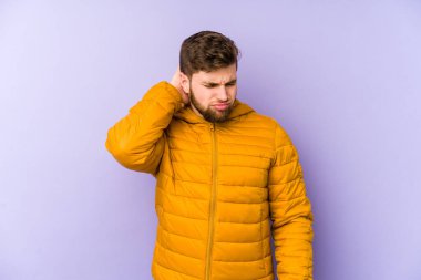 Mor arka planda izole edilmiş genç bir adam stresten dolayı boynu ağrıyor, masaj yapıyor ve elle dokunuyor..