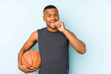 Basketbol oynayan genç Kolombiyalı bir adam tırnak yiyor, gergin ve endişeli..
