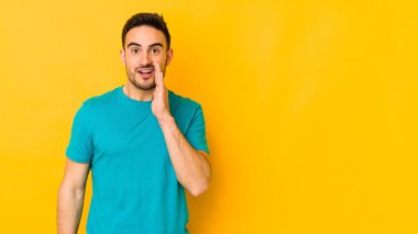 Sarı fırında izole edilmiş genç beyaz adam yüksek sesle bağırıyor, gözleri açık ve elleri gergin tutuyor..