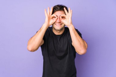 Mor arka planda izole edilmiş genç bir adam heyecanlı..