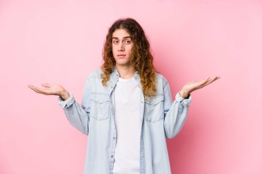 Uzun saçlı adam kuşkuyla poz veriyor ve sorgulamada omuz silkiyor..