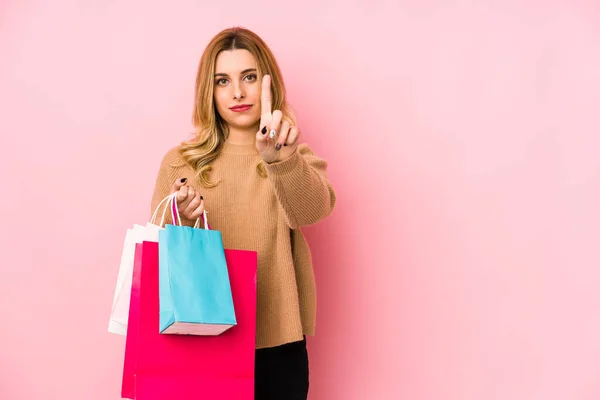 Ung Blond Kvinna Håller Shoppingväskor Isolerade Visar Nummer Ett Med — Stockfoto