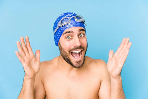 年轻英俊的游泳运动员孤立无援 他得到了一个愉快的惊喜 兴奋地举起双手 — 图库照片