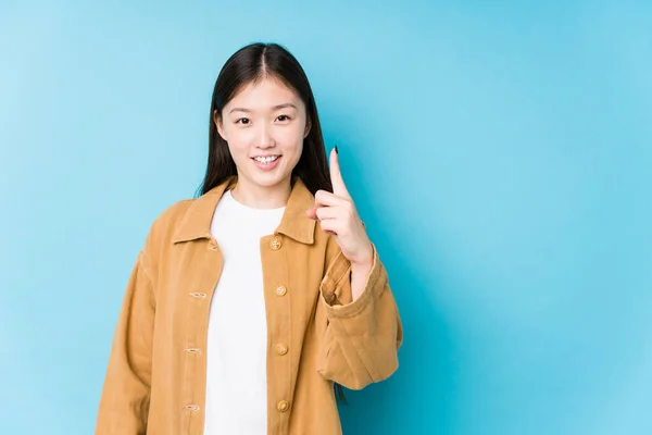 Jonge Chinees Vrouw Poseren Een Blauwe Achtergrond Geïsoleerd Tonen Nummer — Stockfoto