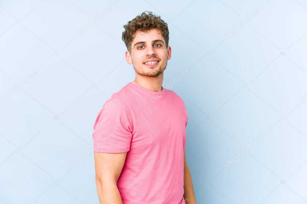 Young blond curly hair caucasian man isolated looks aside smiling, cheerful and pleasant.