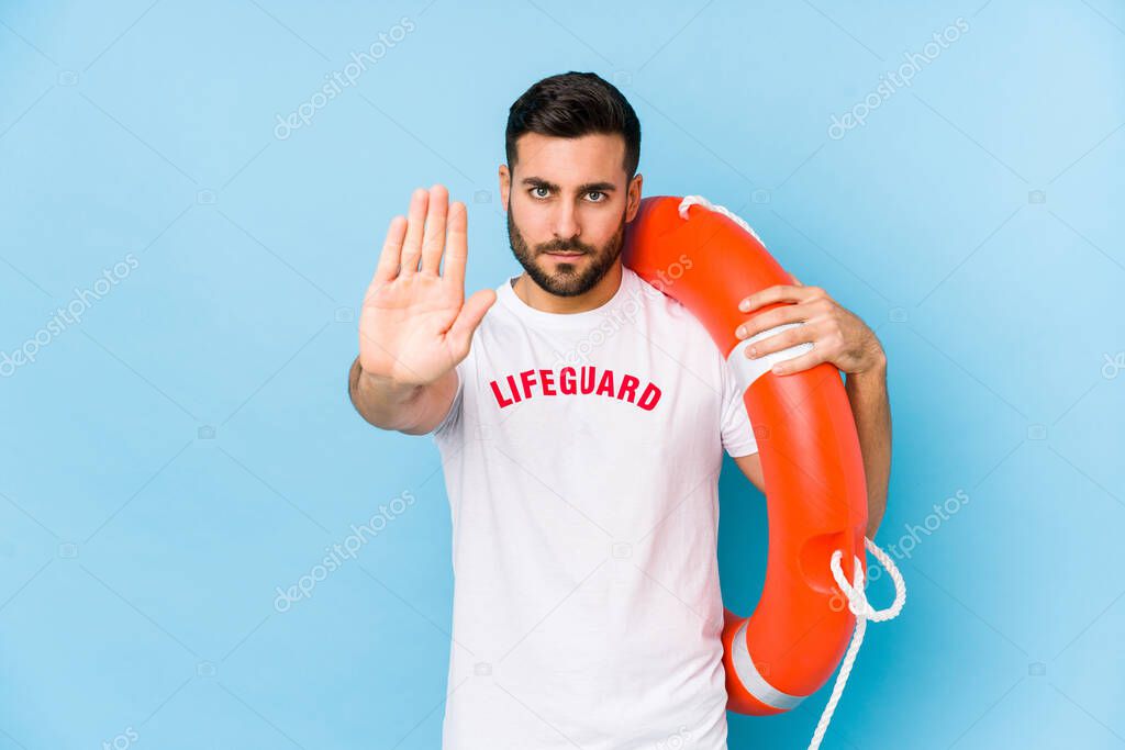 Young handsome lifeguard man isoalted standing with outstretched hand showing stop sign, preventing you.