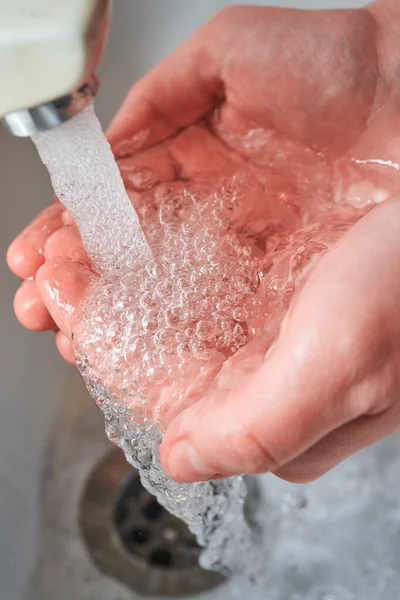 Ręce Trzymające Wodę Dużymi Bąbelkami Opadające Pod Kran Podczas Mycia — Zdjęcie stockowe