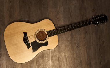 Kahverengi ahşap zeminde 12 telli akustik gitar.